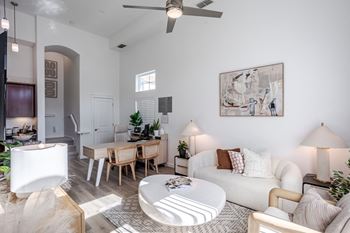 A living room with a white couch, a coffee table, and a ceiling fan.